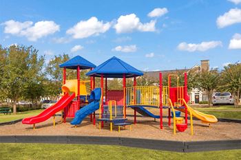 A playground with a blue roof and yellow and red slides